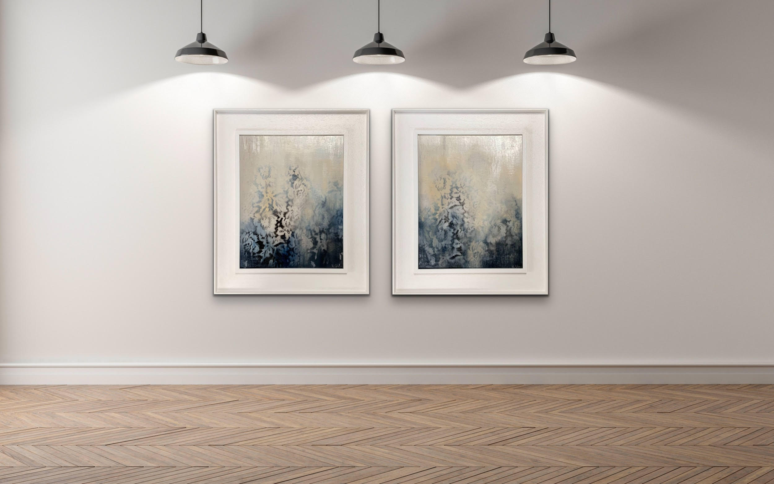 A museum style room with two paintings on a wall and three lamps hanging above.