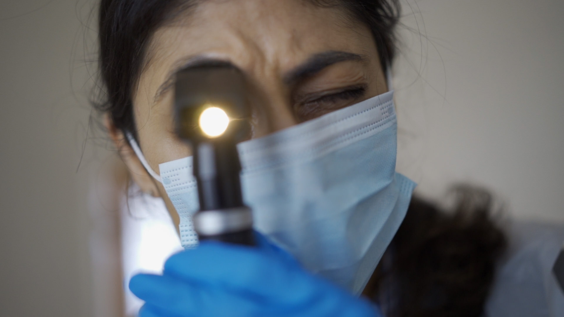 An optometrist shining their equipment at the camera.