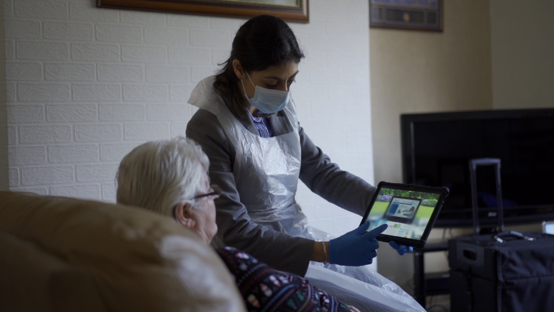 An optometrist shows an elderly woman her results on an iPad.