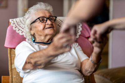 An elderly woman being helped out of her chair.