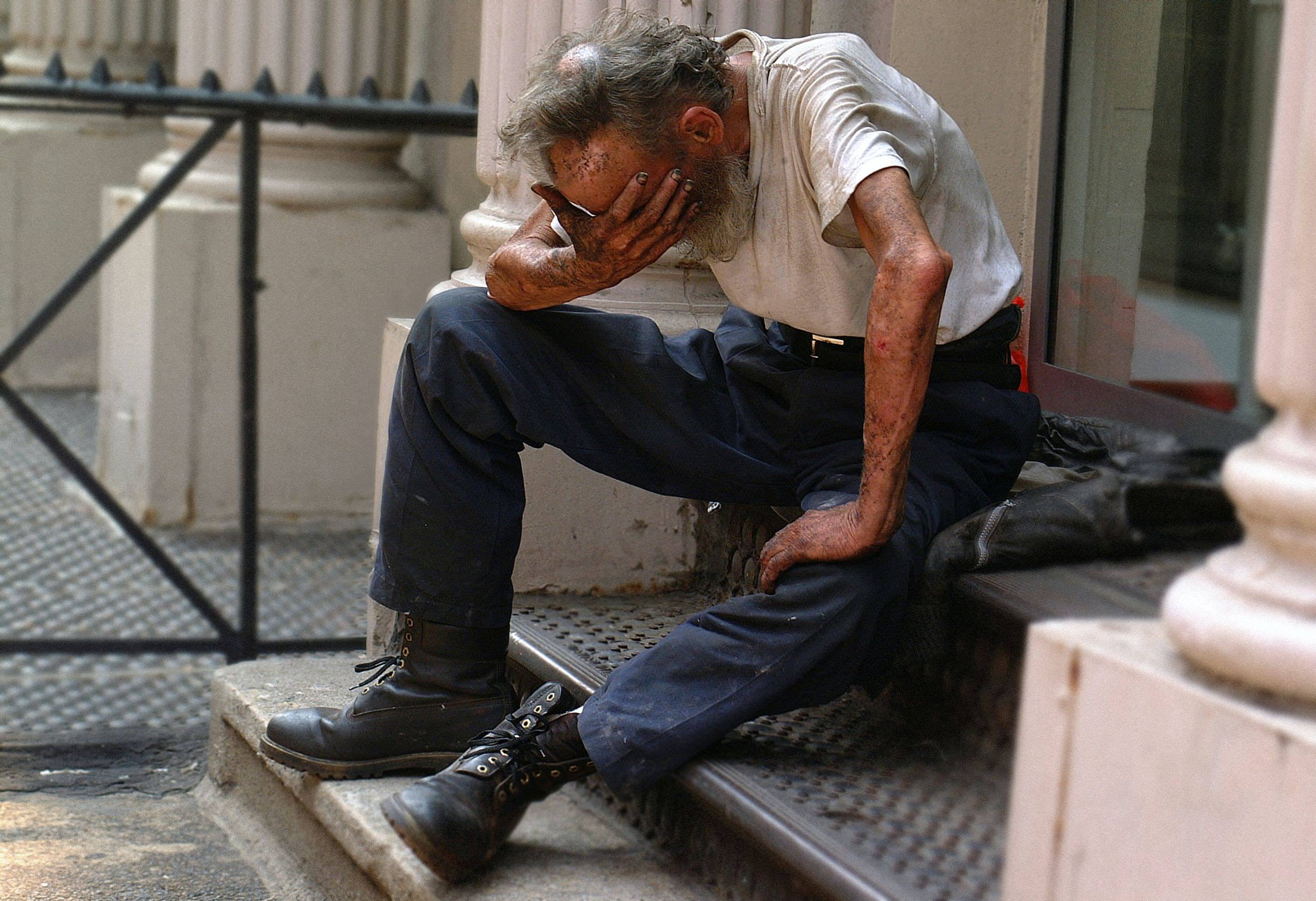 A man sat at the entrance of a building with his head in his hands, distraught.