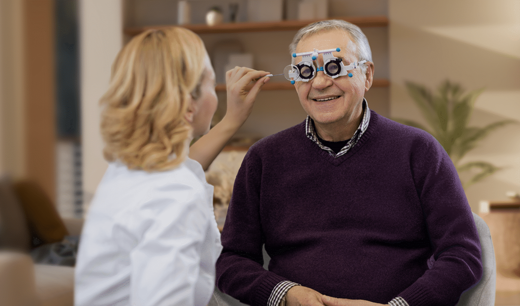 An optometrist performs an eye test on a smiling elderly man.