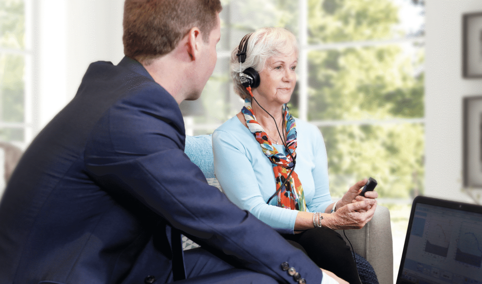 An audiologist performs a hearing test on an elderly woman.